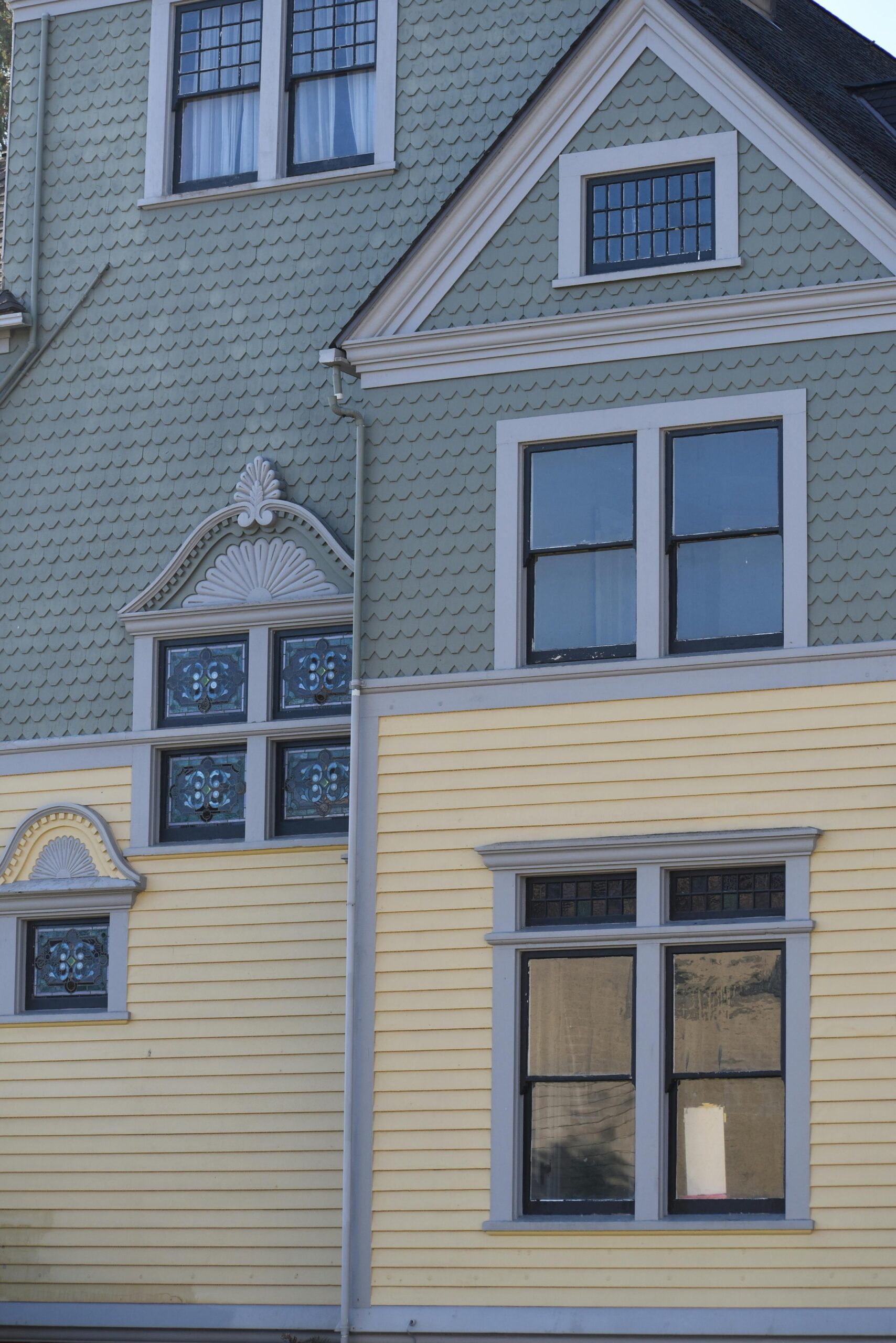 Close-up of a Victorian townhouse facade featuring pastel colors, ornate windows, and texture.